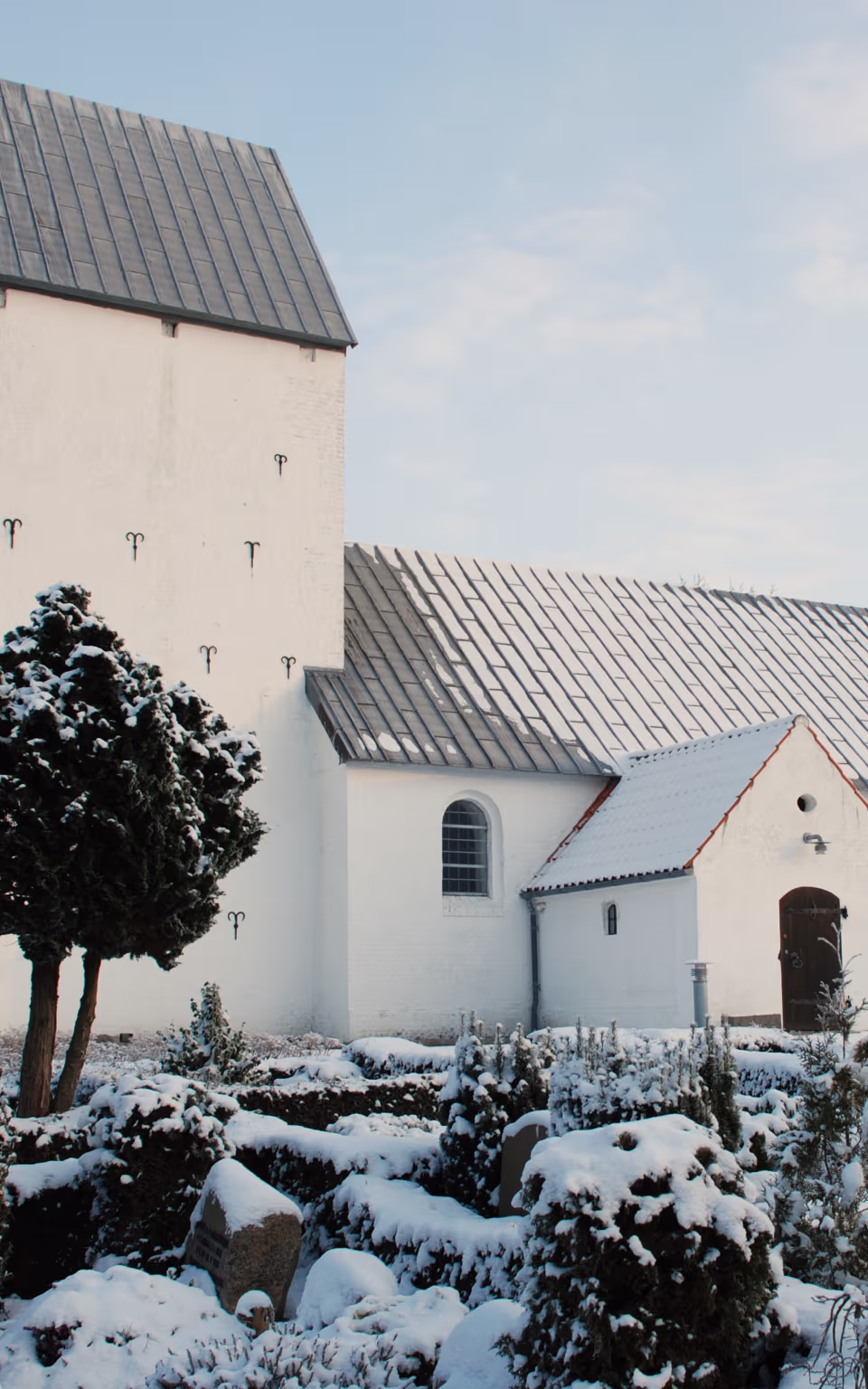 Lydum Kirke med snedækket kirkegård og hvide hække foran