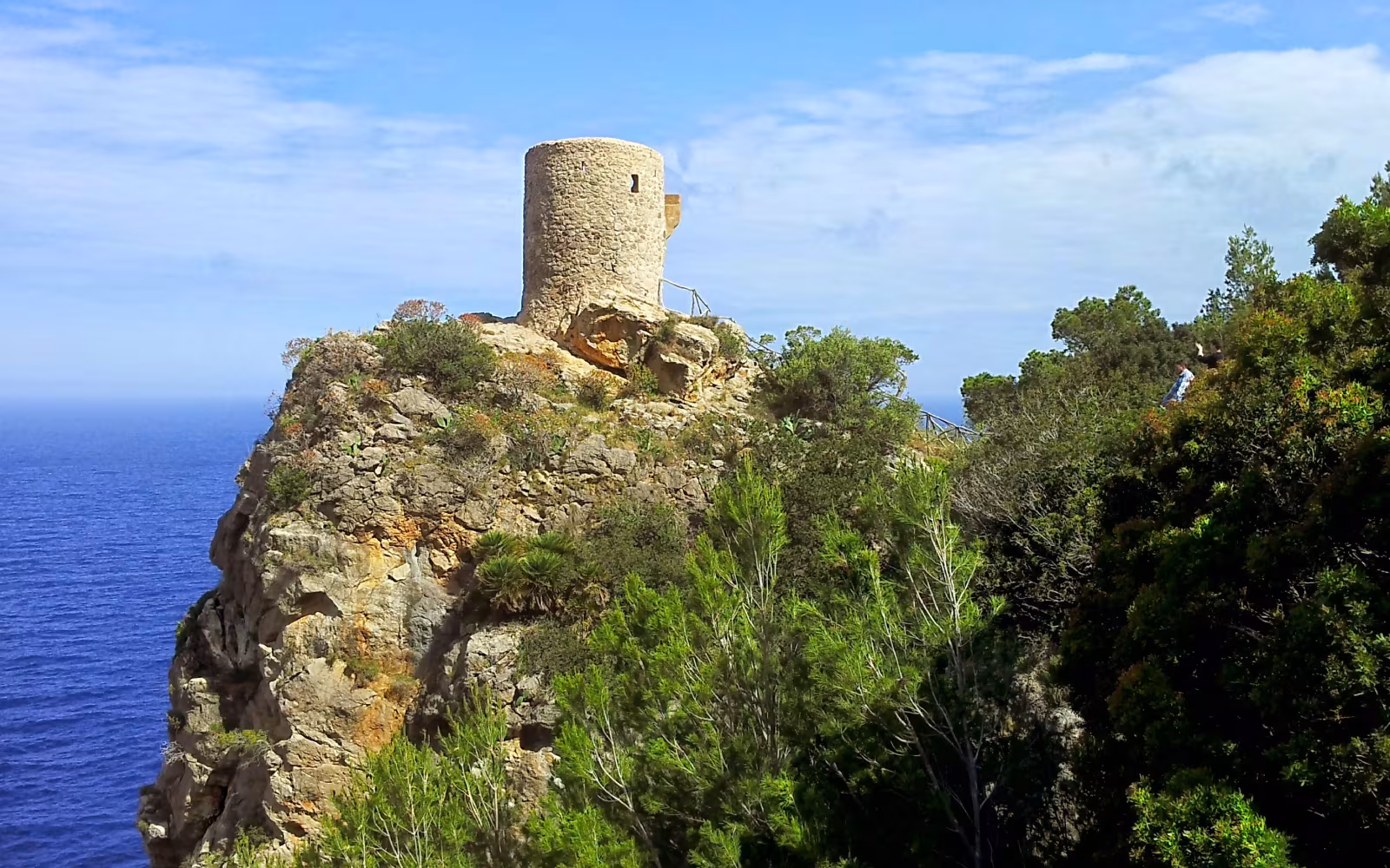 Torre de Verger på klippe over havet omgivet af grøn bevoksning