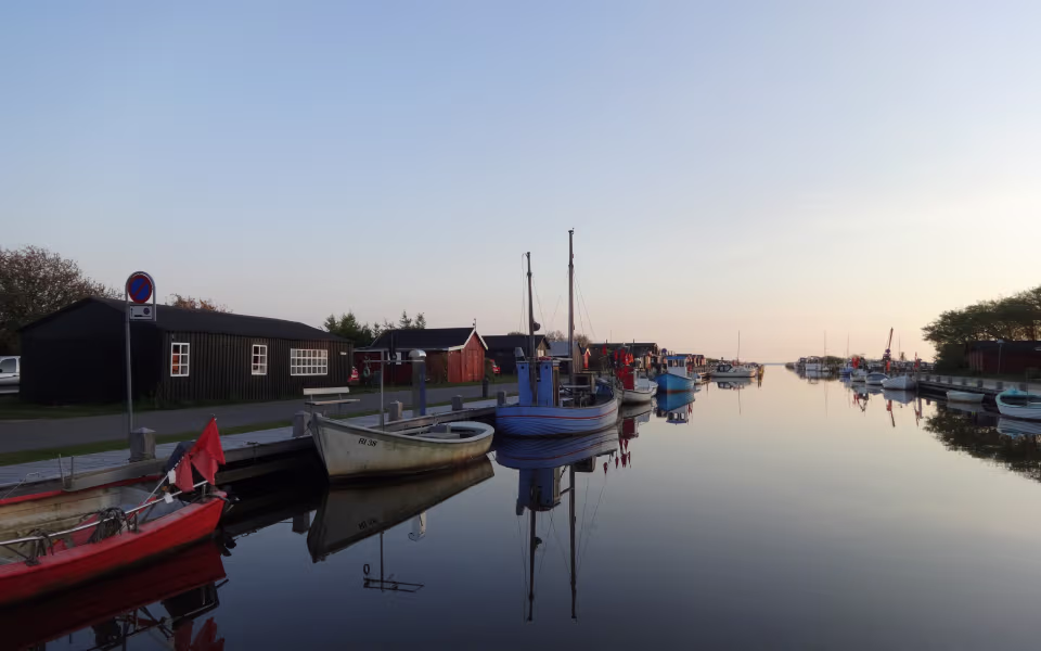 Både ligger spejlblankt i Stauning Havn foran røde og sorte havnehuse