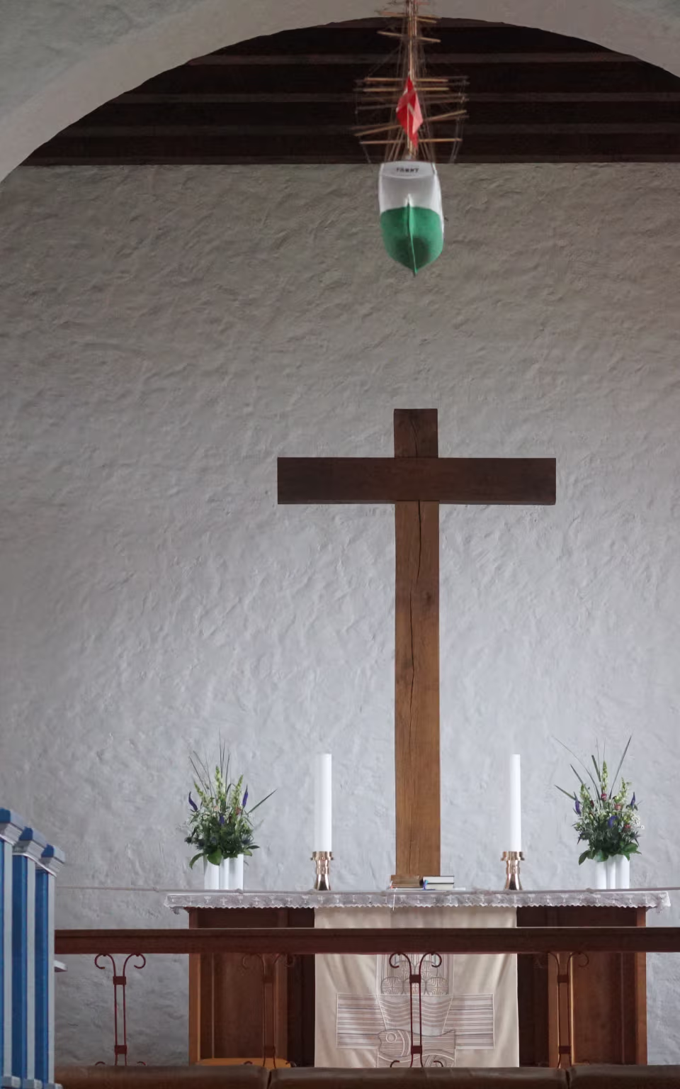 Alter med stort trækors og blå kirkebænke i Helligåndskirken