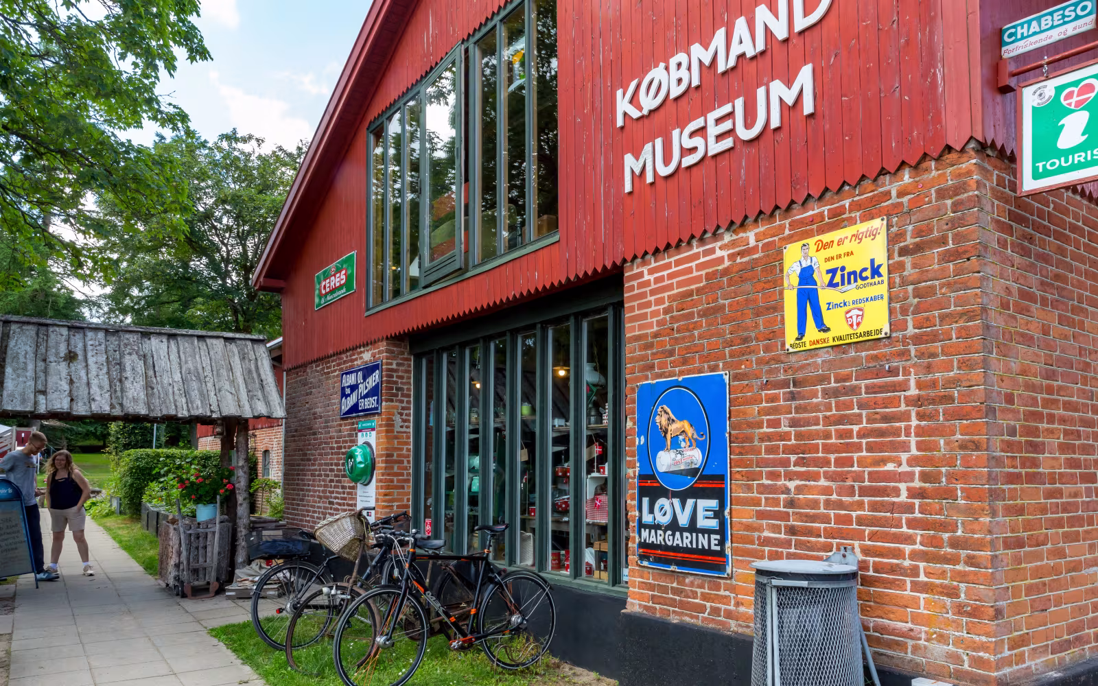 Rød facade ved Bindeballe Købmandsgård med gamle reklameskilte og cykler foran