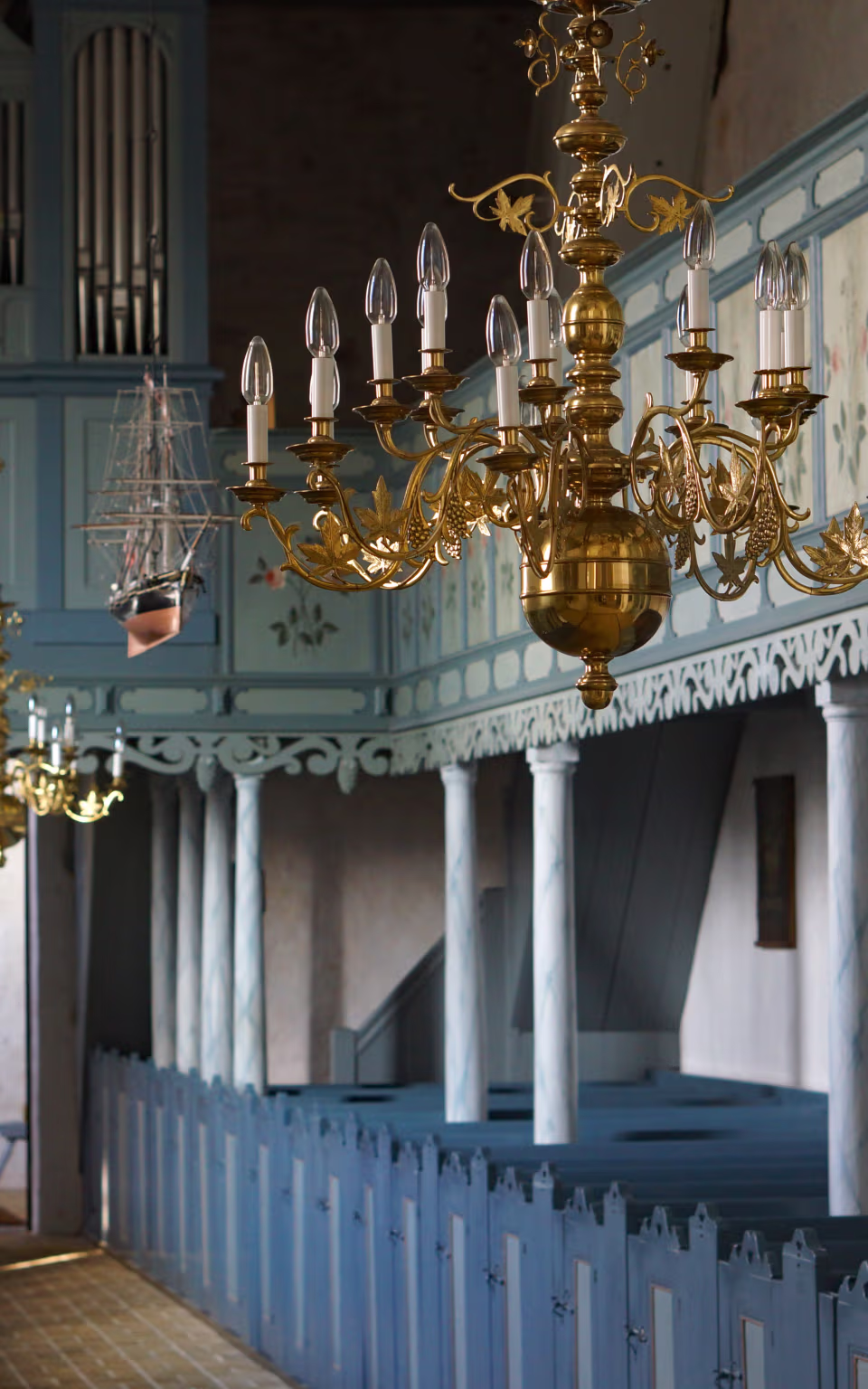 Messinglysekrone foran orgel og blå kirkebænke i Ballum Kirke
