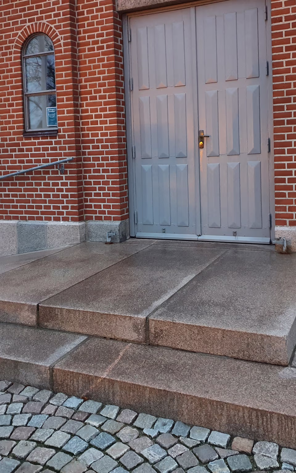 Indgang med grå dobbeltdør og røde mursten ved Grene Kirke