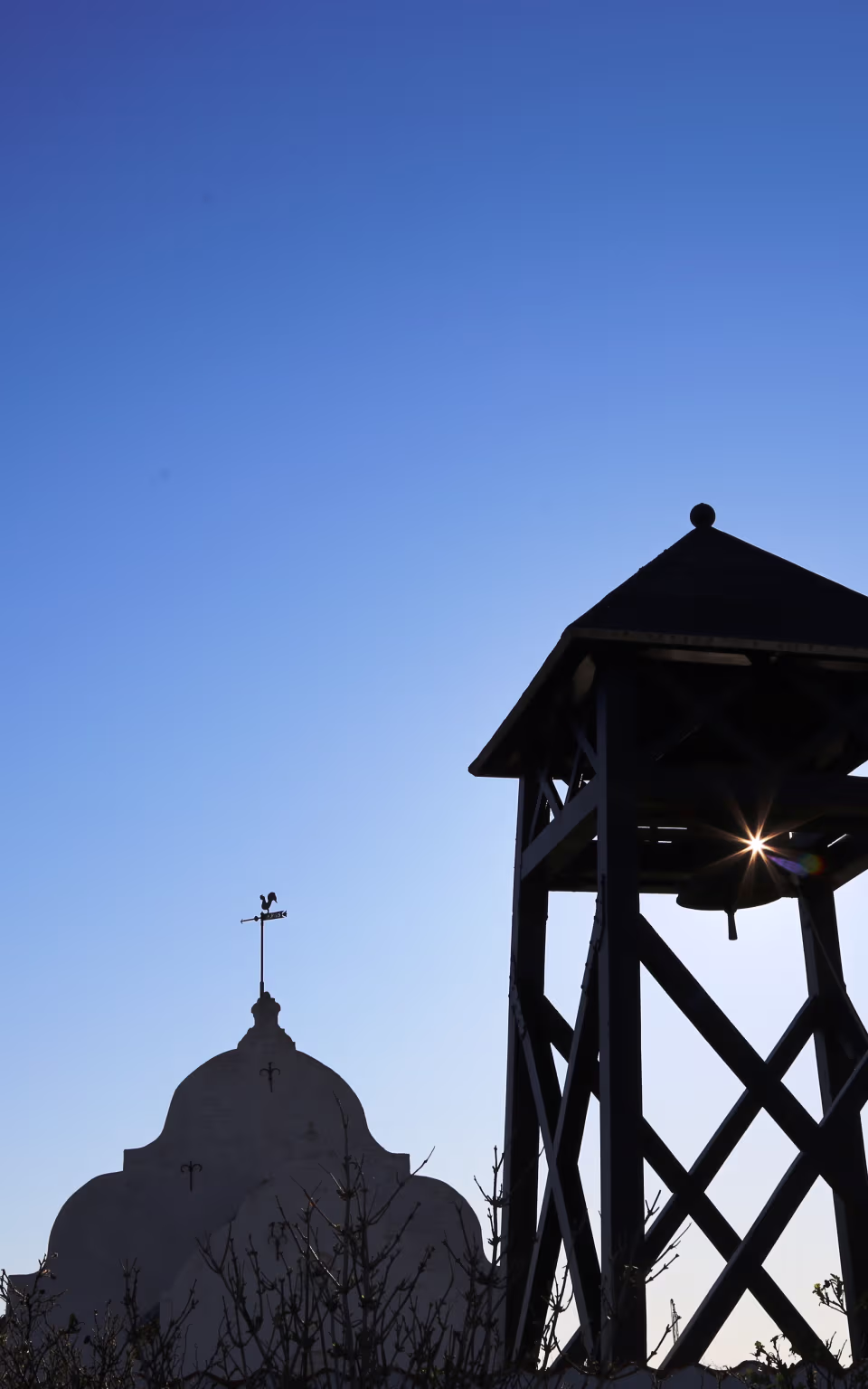 Kirke og klokketårn på Mandø i silhuet under blå himmel