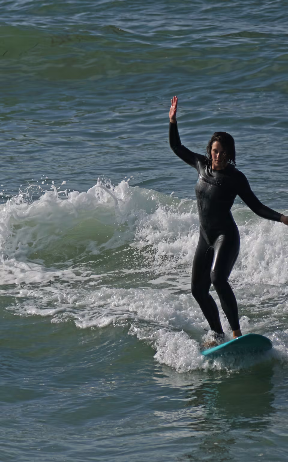 Surfer i våddragt balancerer i brændingen ved Høfde Q