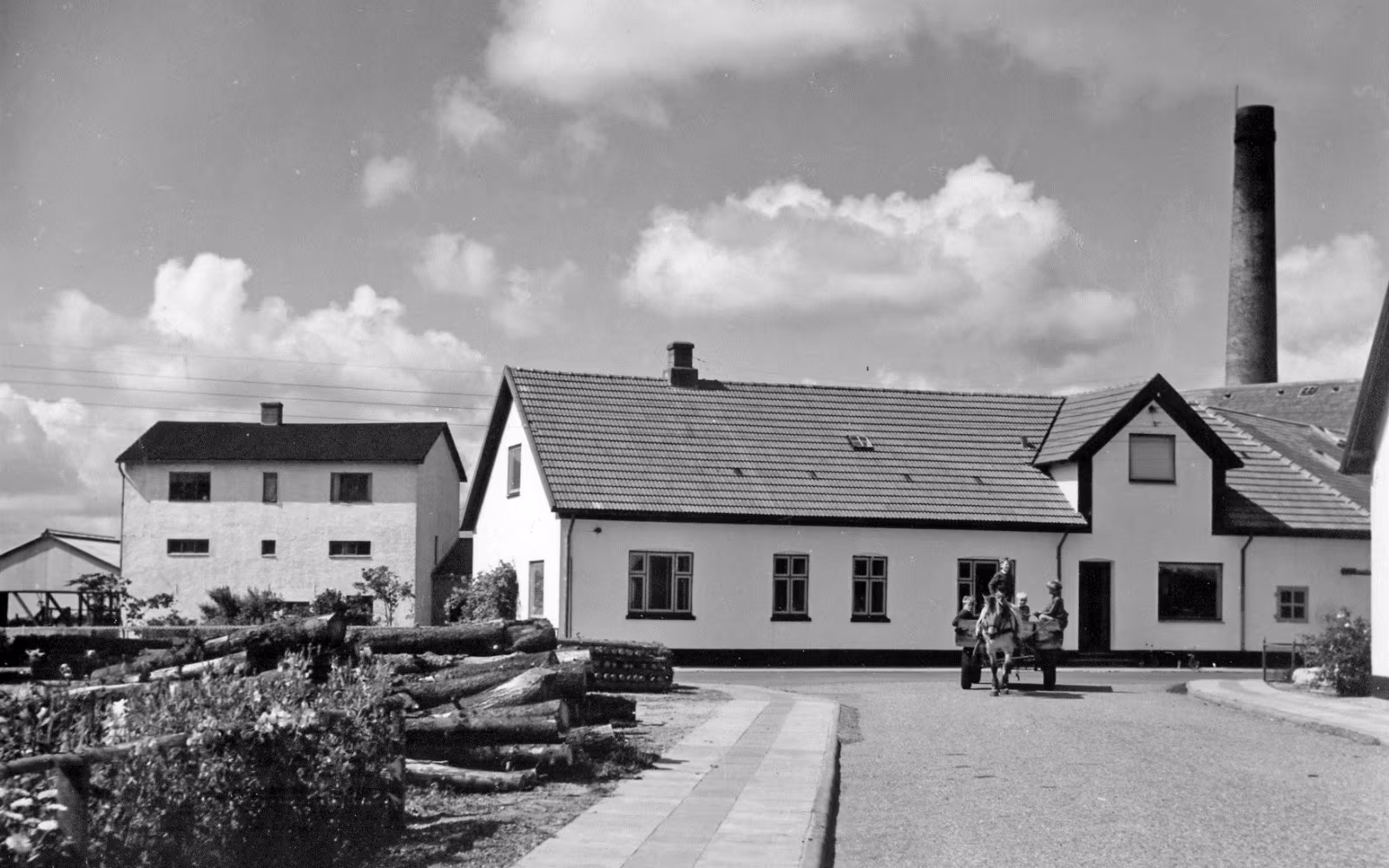 Hestevogn foran Skovlund Andelsmejeri med lyse bygninger og høj skorsten