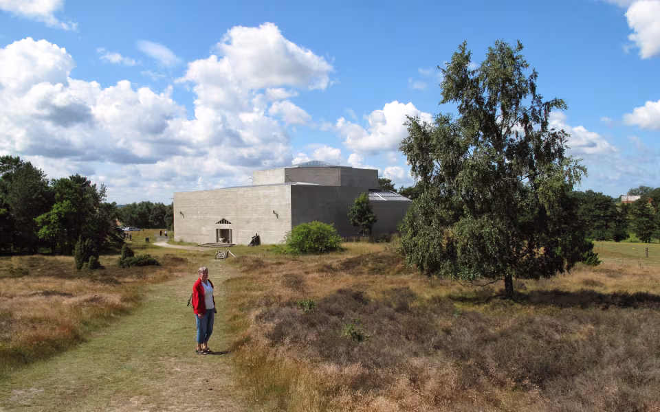 Rudolph Tegners Museum bag lyngklædt sti med besøgende under skyet sommerhimmel