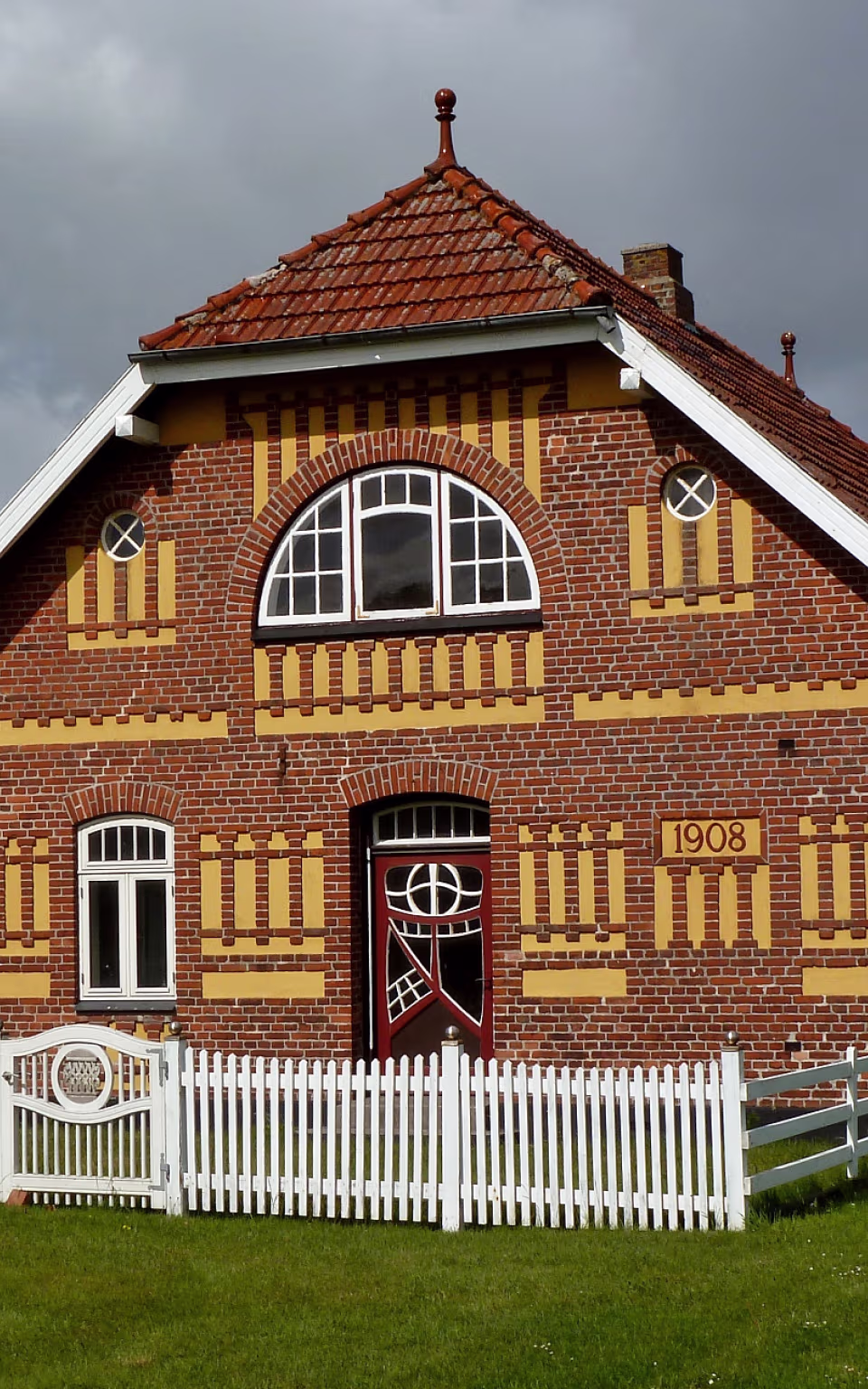 Rødstenshus fra 1908 med hvidt stakit i Hjerpsted By
