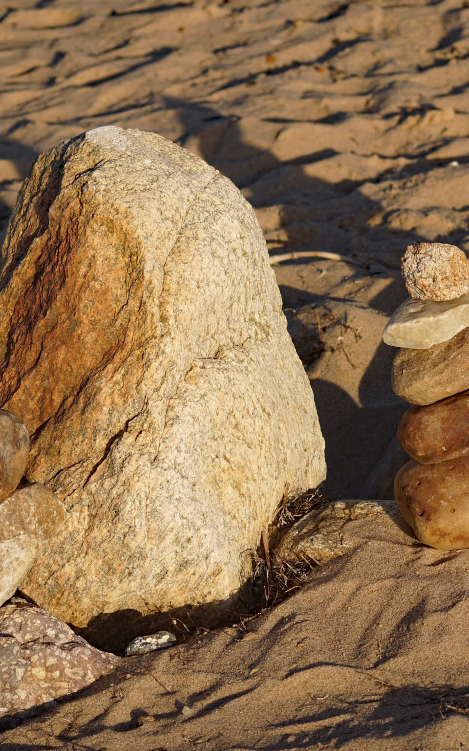 Stablede sten og stor klippe på sandet ved Skaven Strand