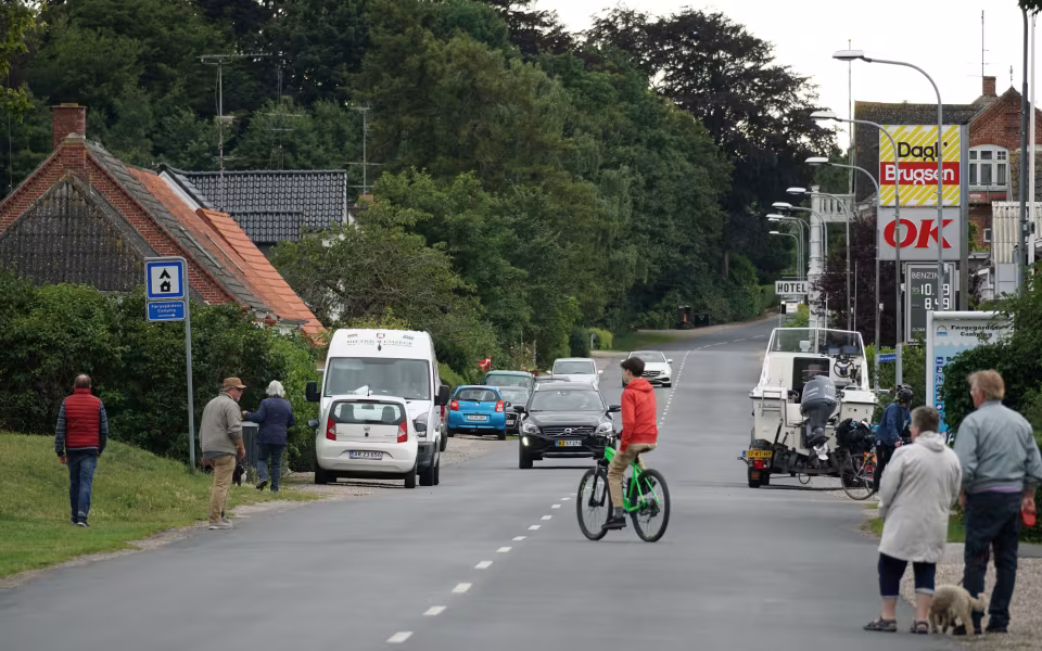 Vej gennem Spodsbjerg med biler, fodgængere, cyklist og Brugsen-skilt