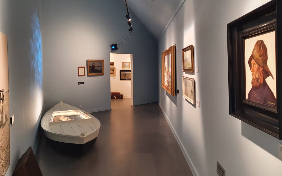 Udstillingsrum på Nymindegab Museum med malerier, bådmodel og stor fiskeinstallation