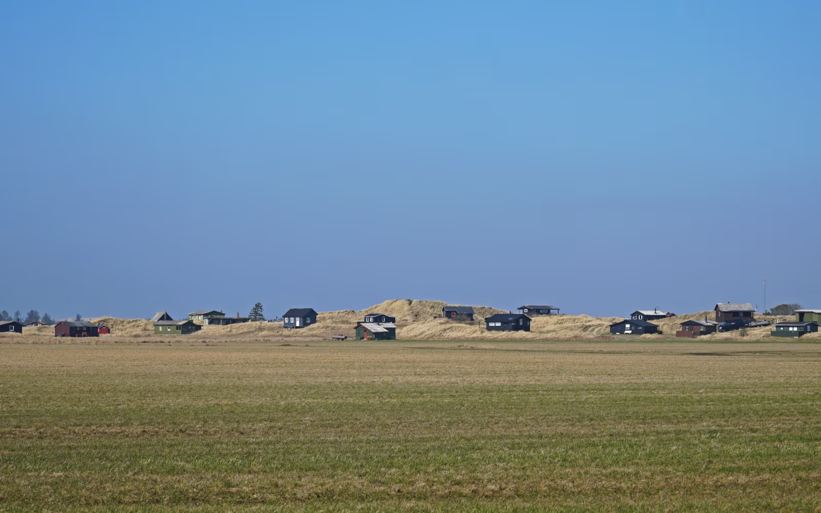 Sommerhuse i klitterne ved Tipperhalvøen under stor blå himmel