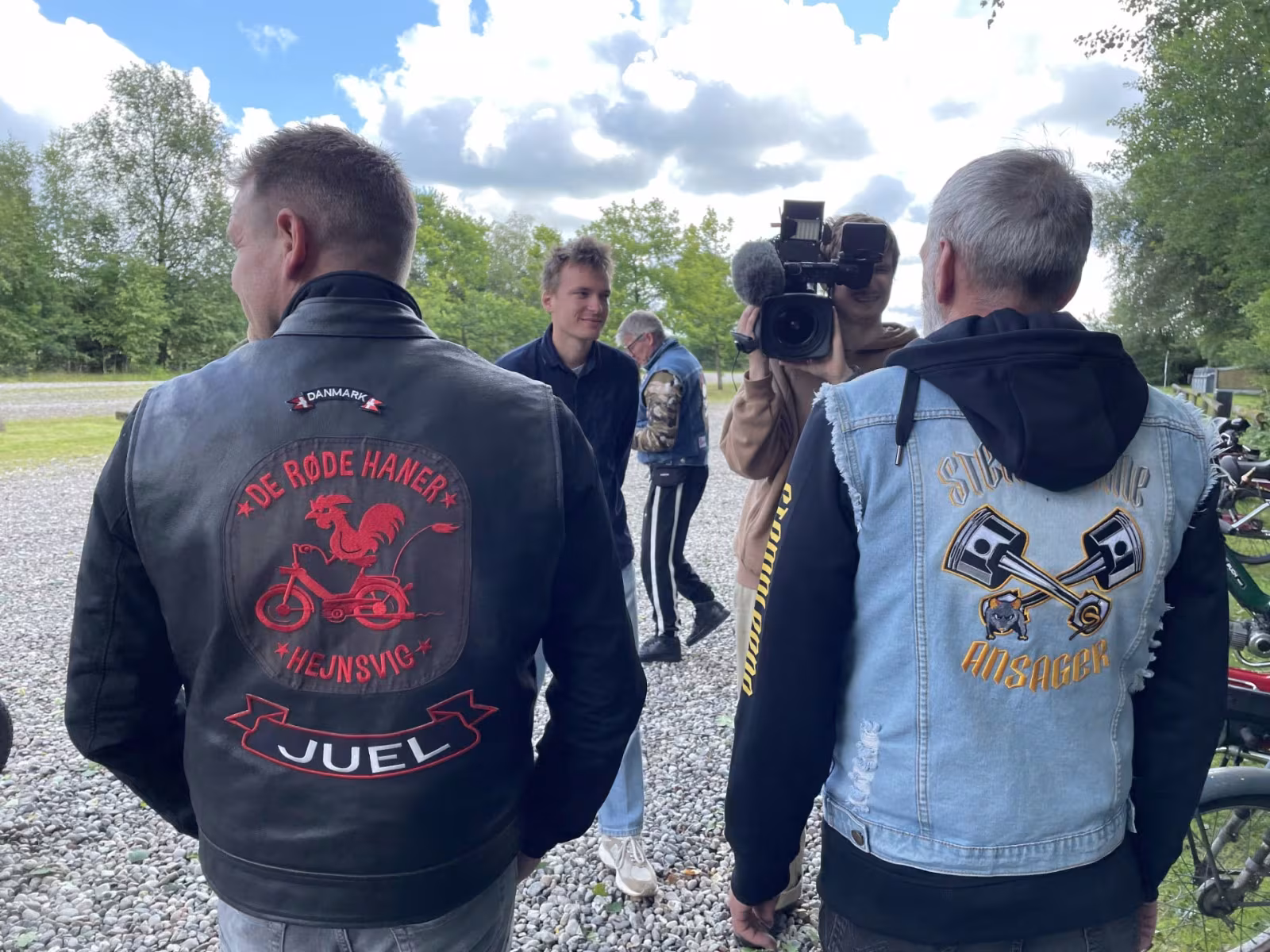 På billedet ses TV2 filme en knallertentusiast fra Stemplerne med klubbens rygmærke. Ved siden af står en medlem fra naboklubben i Hejnsvig med deres eget rygmærke. Fælles passion og fællesskab mellem veteranknallertklubberne vises frem i aftenens nyheder kl. 19:00 på TV2.