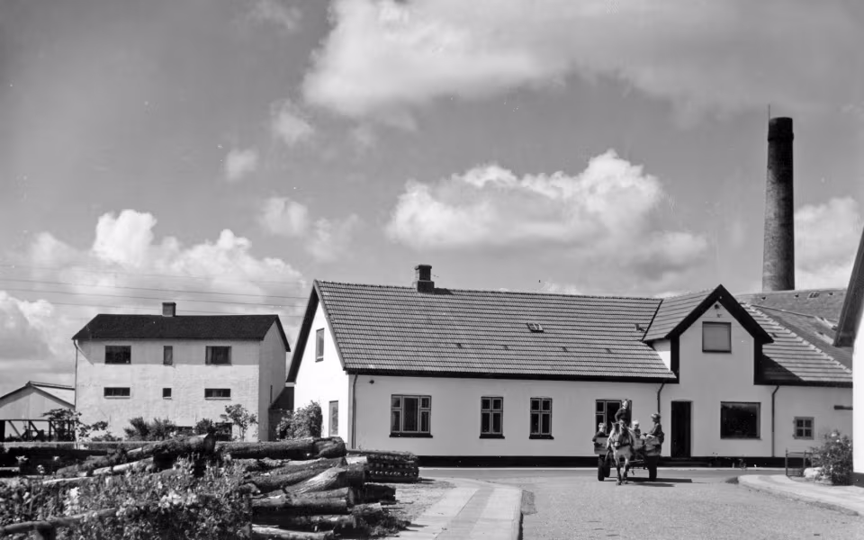 Hestevogn foran Skovlund Andelsmejeri med lyse bygninger og høj skorsten