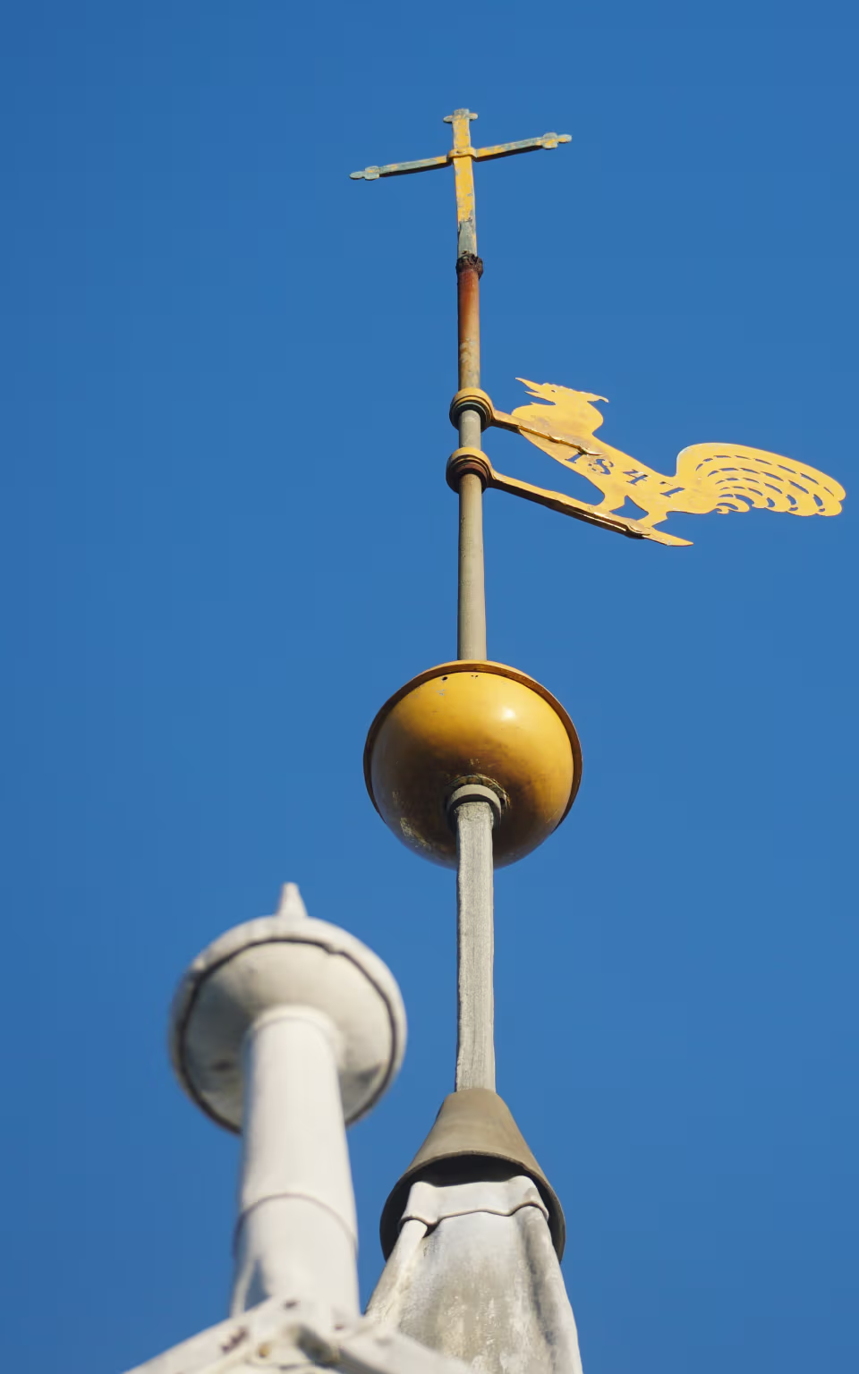 Gylden vejrhane på Vester Vedsted Kirke mod klar blå himmel