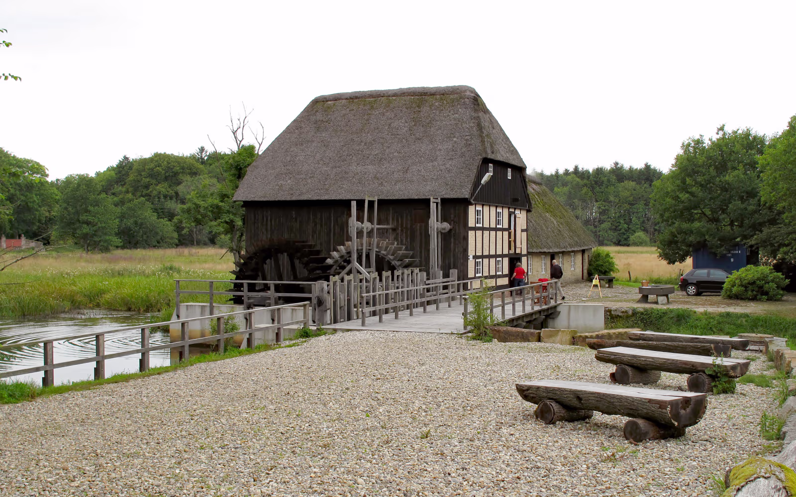 Stråtækt vandmølle ved Nørholm Vandmølle med træbroer over roligt vand