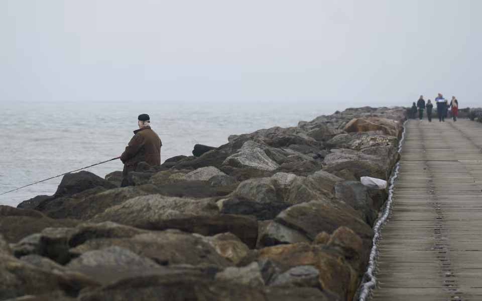 Fiskere på Hvide Sande Sydmole mellem store sten og hav