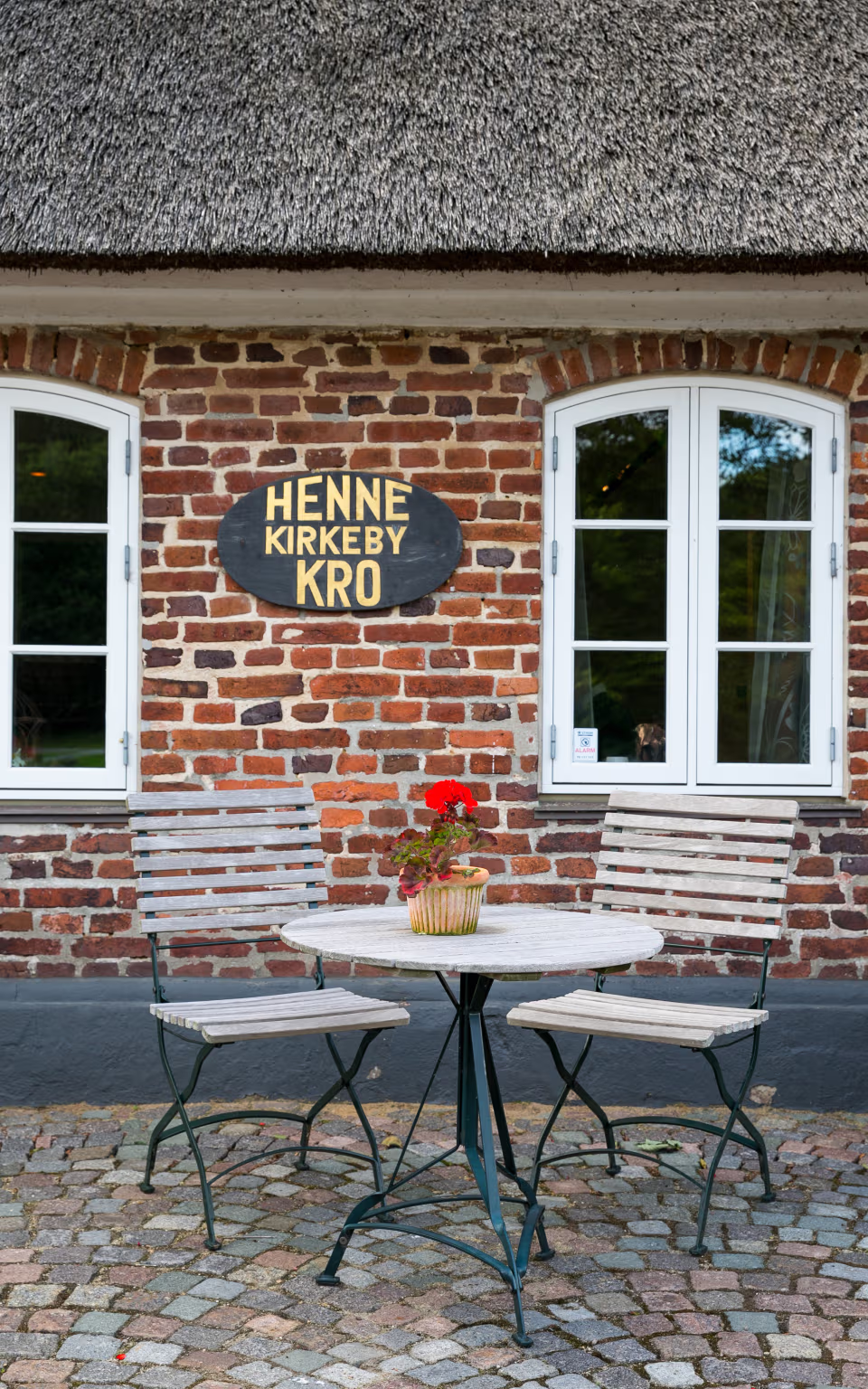 Bord og bænke foran Henne Kirkeby Kros stråtækte murstensfacade med skilt