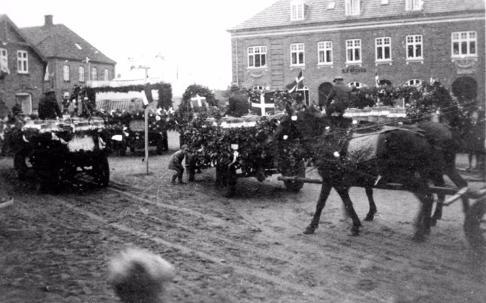 Mælkekuskenes parade med pyntede vogne gennem Ansager i anledning af mejeriets 50 års jubilæum passerer Torvet
