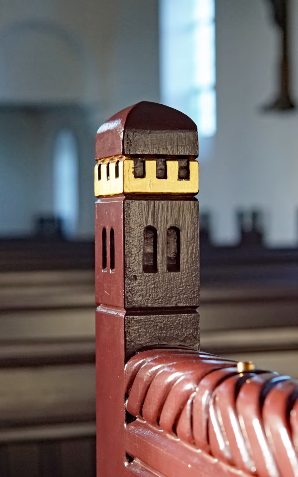 Udskåret kirkebænk i Skovlund Kirke med sløret kirkerum bagved
