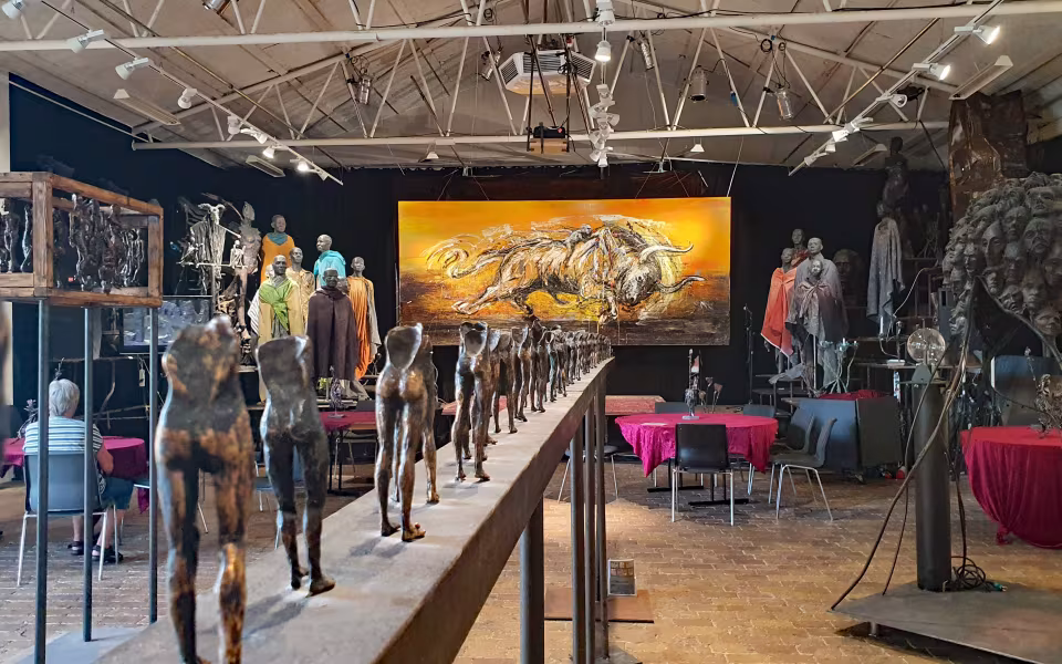 Bronzeskulpturer på buet podie i Galleri Galschiøt med stort orange maleri bagved