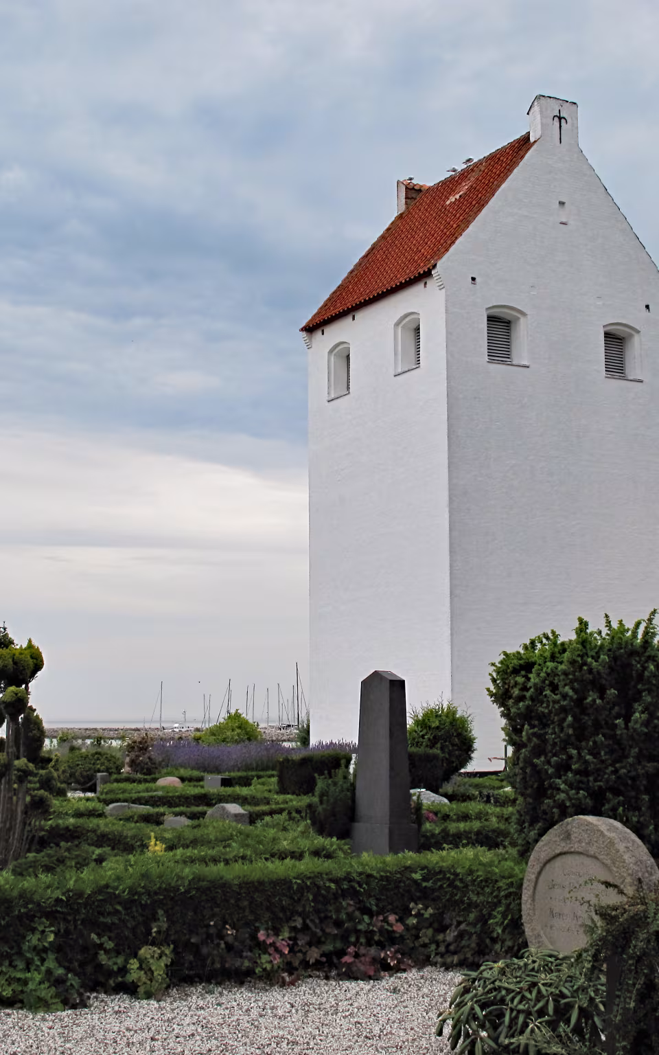 Hvid kirke ved Endelave kirkegård med røde tegltage og gravsteder