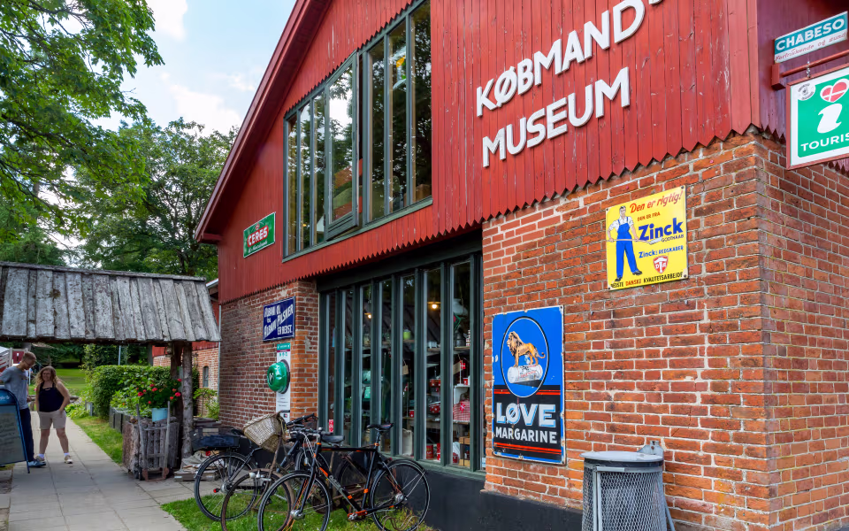 Rød facade ved Bindeballe Købmandsgård med gamle reklameskilte og cykler foran