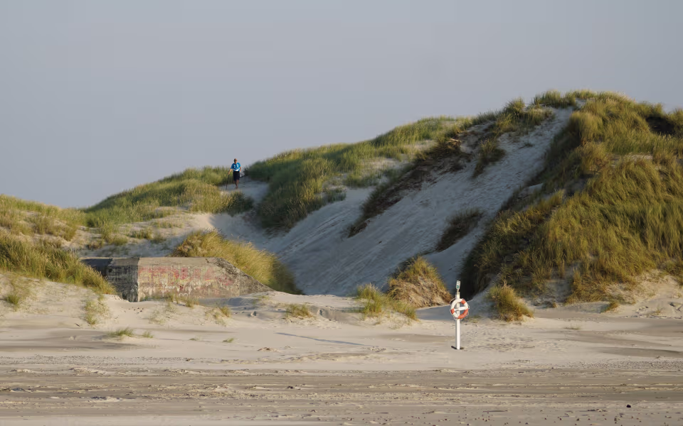 Mand vandrer på sti mellem klitter og bunker ved Børsmose Strand