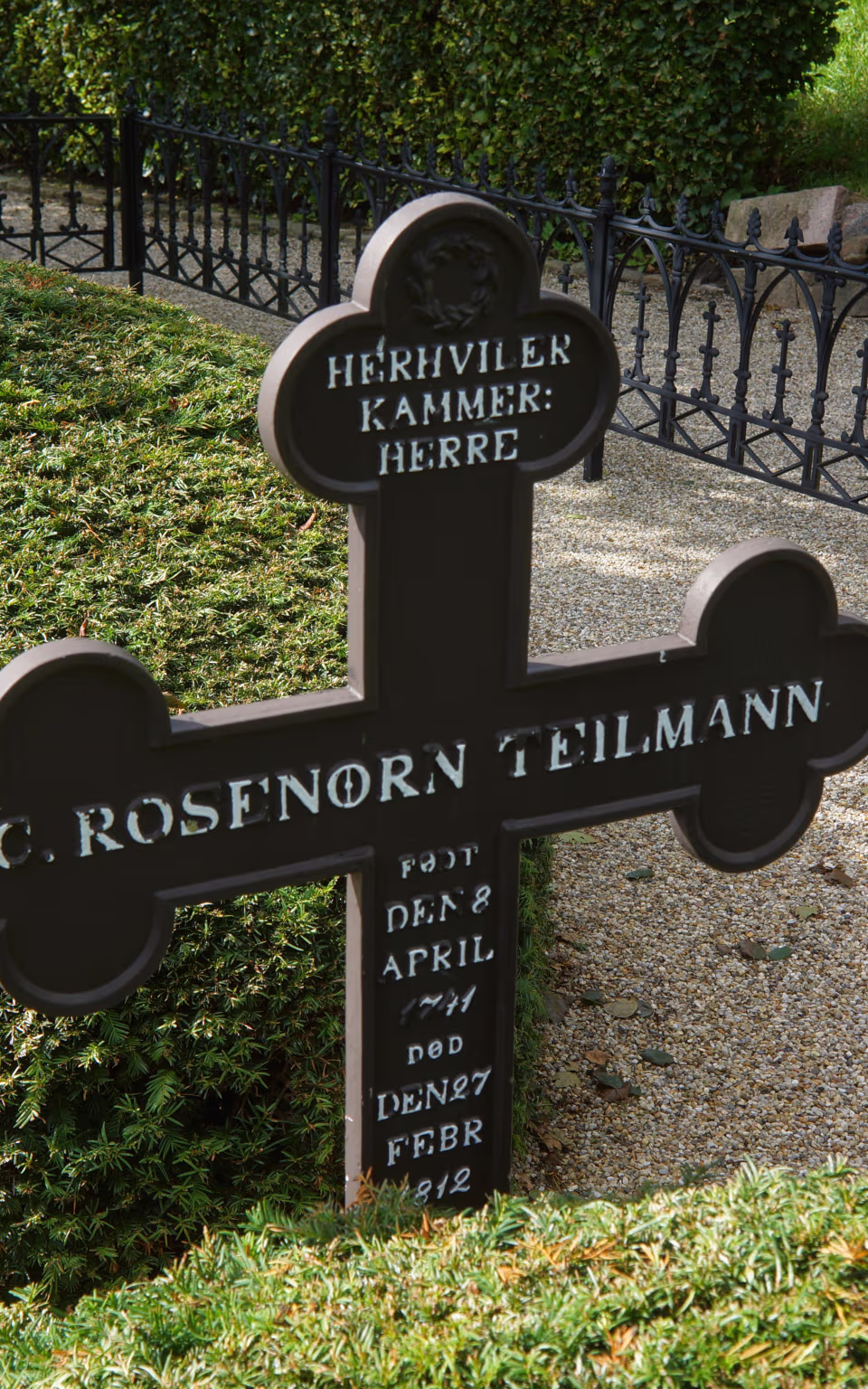 Gravsten og sorte jerngitre på kirkegården ved Thorstrup Kirke