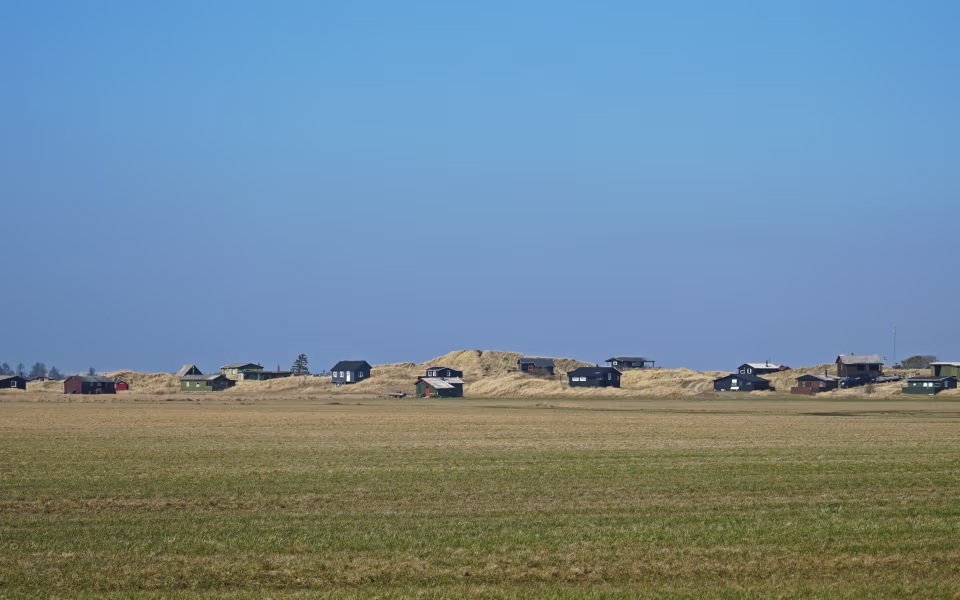 Sommerhuse i klitterne ved Tipperhalvøen under stor blå himmel