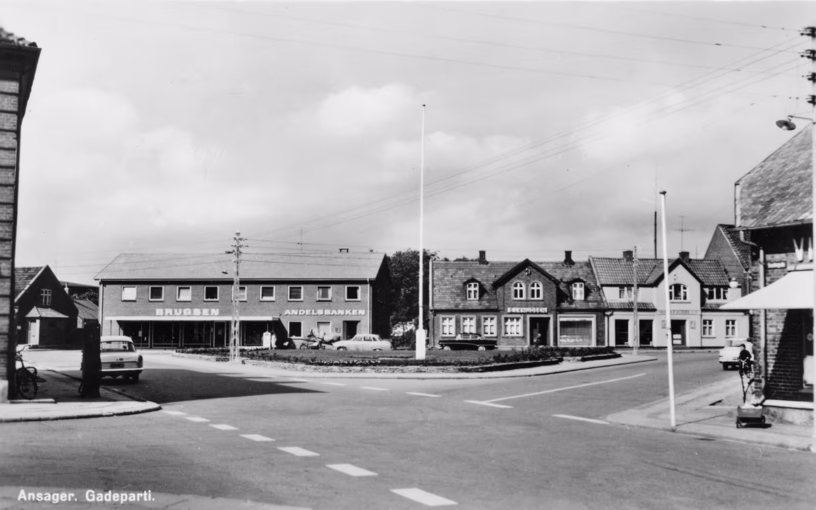 Gadeparti ved Torvet med Brugsen, Andelsbanken, parkerede biler og flagstænger