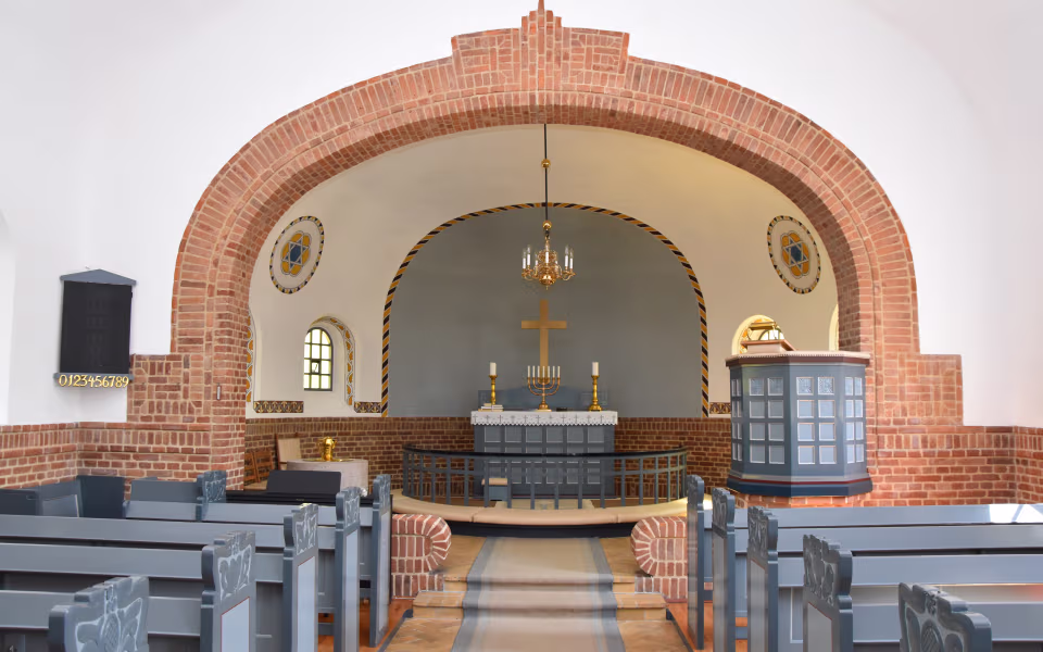 Kirkerum i Urup Kirke med murstensbuer, alter, prædikestol og grå kirkebænke