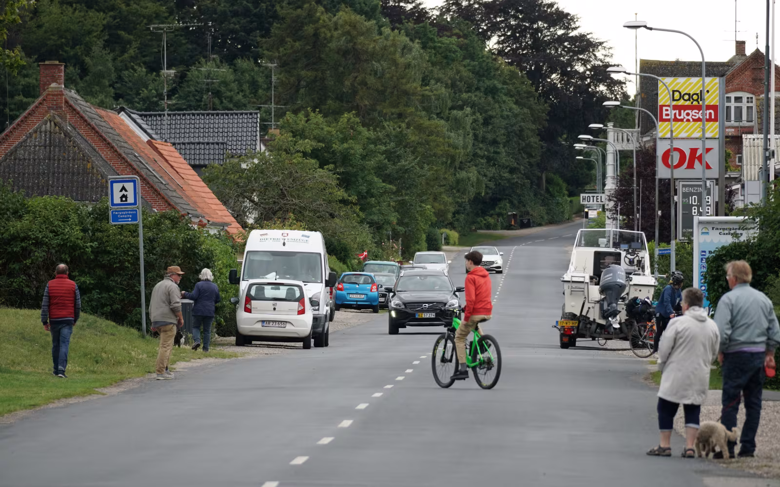 Vej gennem Spodsbjerg med biler, fodgængere, cyklist og Brugsen-skilt