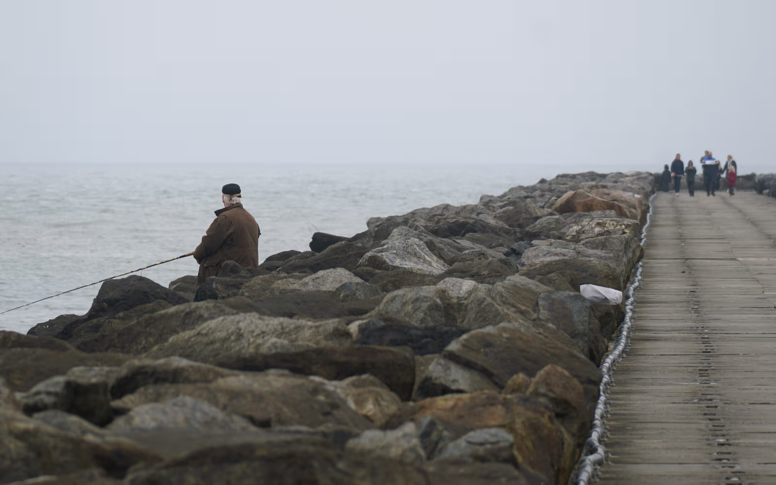 Fiskere på Hvide Sande Sydmole mellem store sten og hav