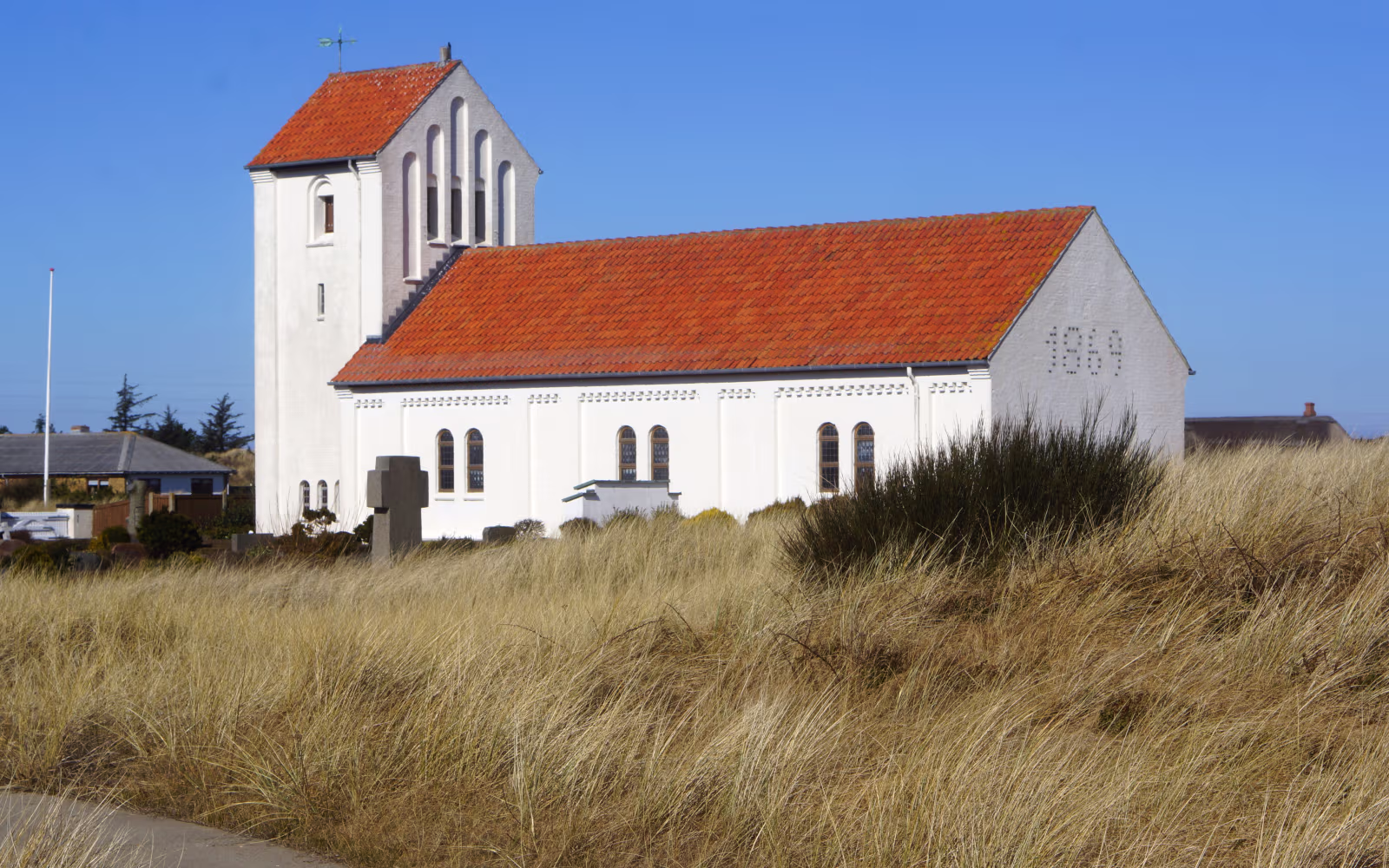 Nr. Lyngvig Kirke med rødt tegltag bag klitter med marehalm