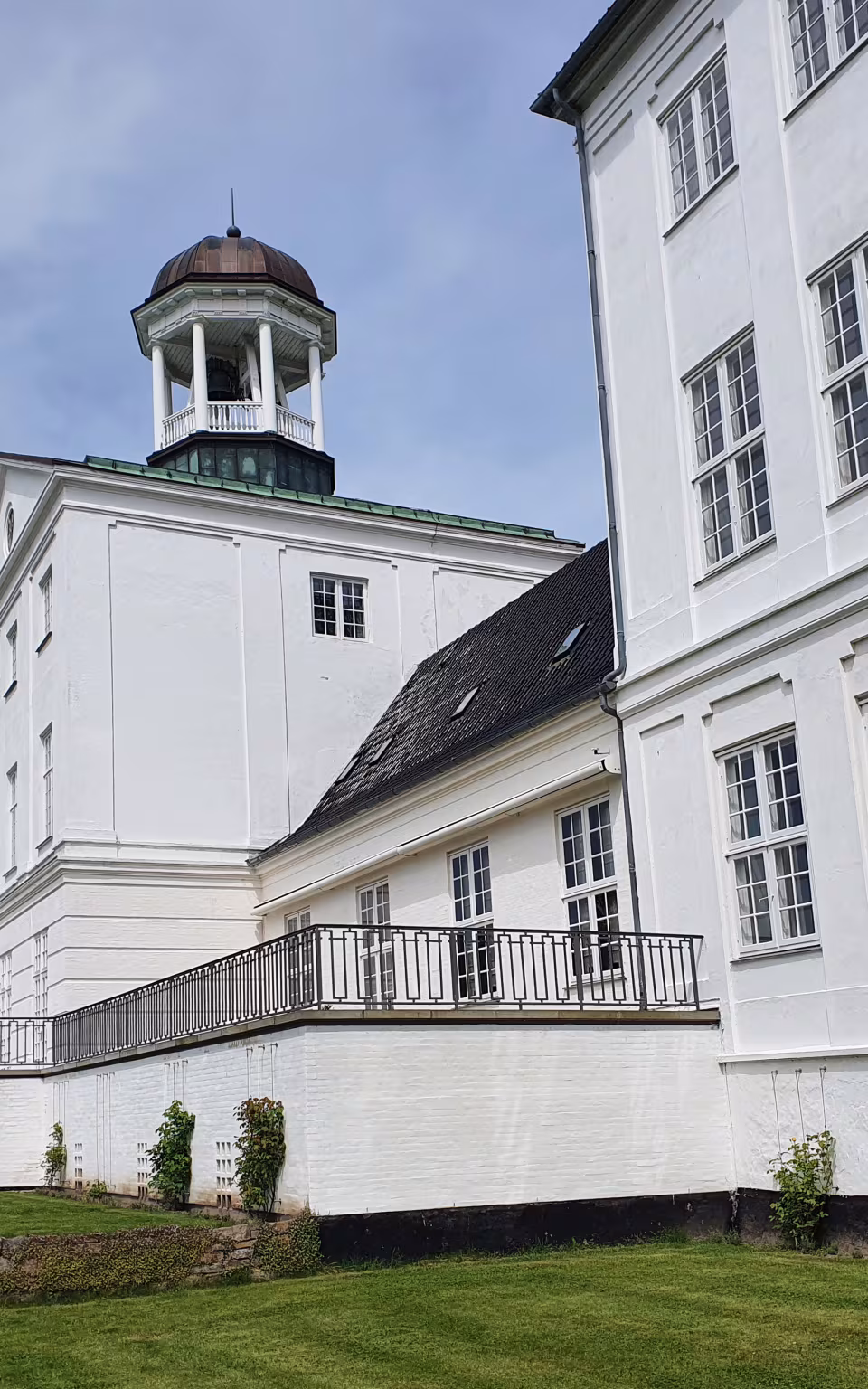 Hvid slotsfacade og tårn ved Gråsten Slot med trappe og terrasse