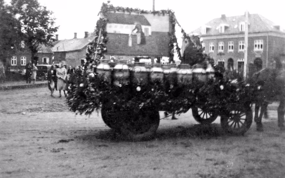 Mælkekuskenes parade med pyntede vogne gennem Ansager i anledning af mejeriets 50 års jubilæum passerer Torvet