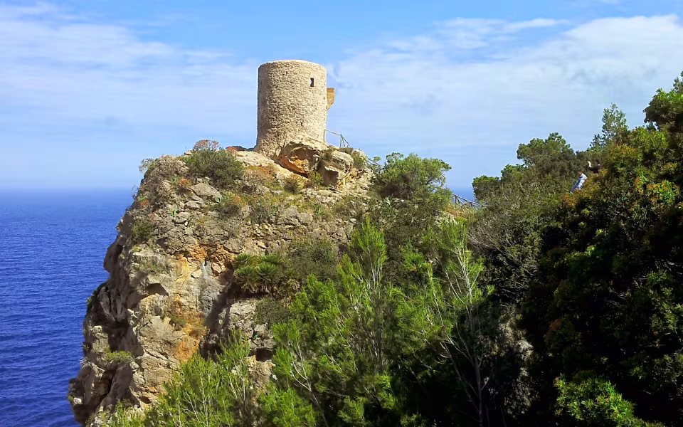 Torre de Verger på klippe over havet omgivet af grøn bevoksning