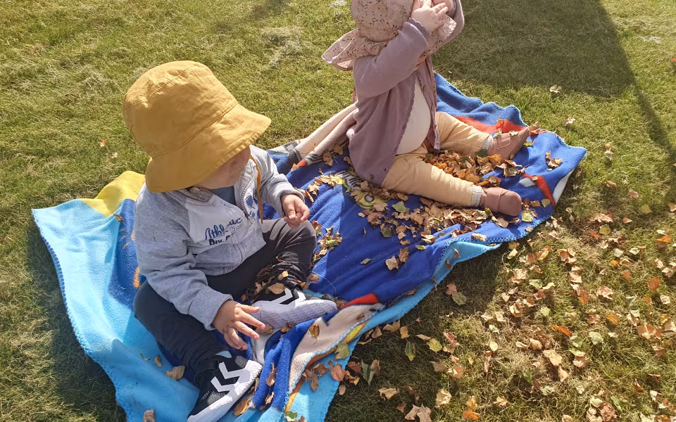 Børn fra Ansager dagpleje skaber et efterårsregn af birkeblade fra kirketræerne. Smil, latter og bare tæer dominerer i sanse-haven på denne dejlige sensommerdag
