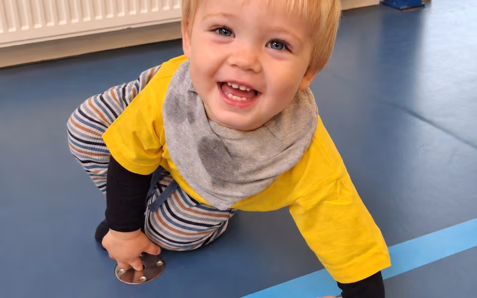 Dagplejere og børn mødes til bevægelse i Skovlund-Ansager Hallen, hvor de nye gule trøjer er i brug blandt farverige redskaber.