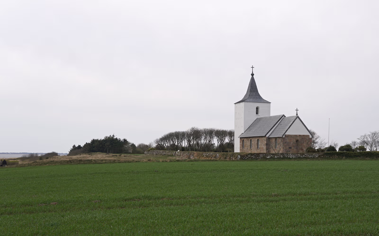 Gammelsogns Kirke med hvidt tårn ved grøn mark og kyst