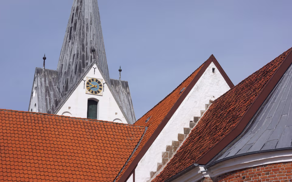 Kirketårn og ur på Sct. Jacobi Kirke over røde tegltage