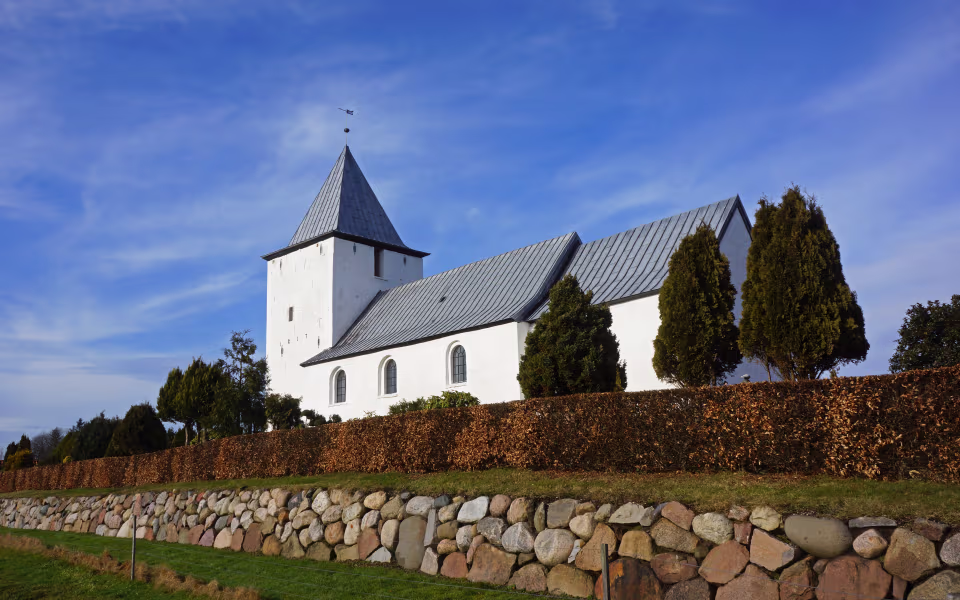 Kirketårn ved Vester Starup Kirke over stengærde og klippede hække