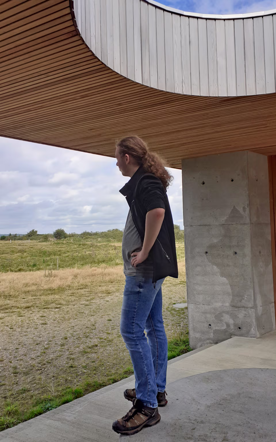 Person står under træbeklædt udsigtspavillon ved Filsø med åbent landskab bagved