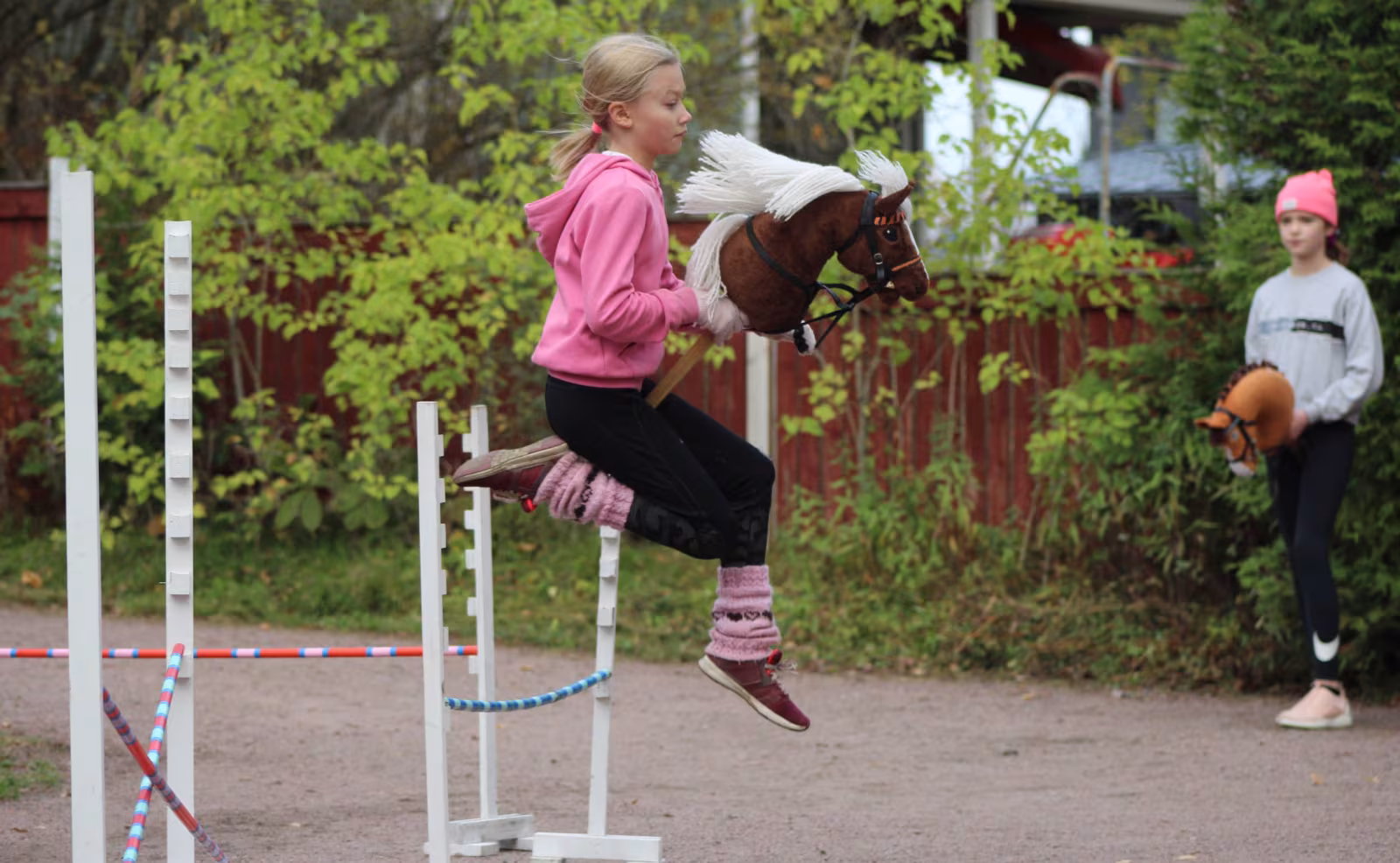 To piger demonstrerer deres færdigheder og entusiasme i en kæphestespringskonkurrence, hvor de elegant springer over forhindringerne og dermed bringer fantasien til live i denne legende sport